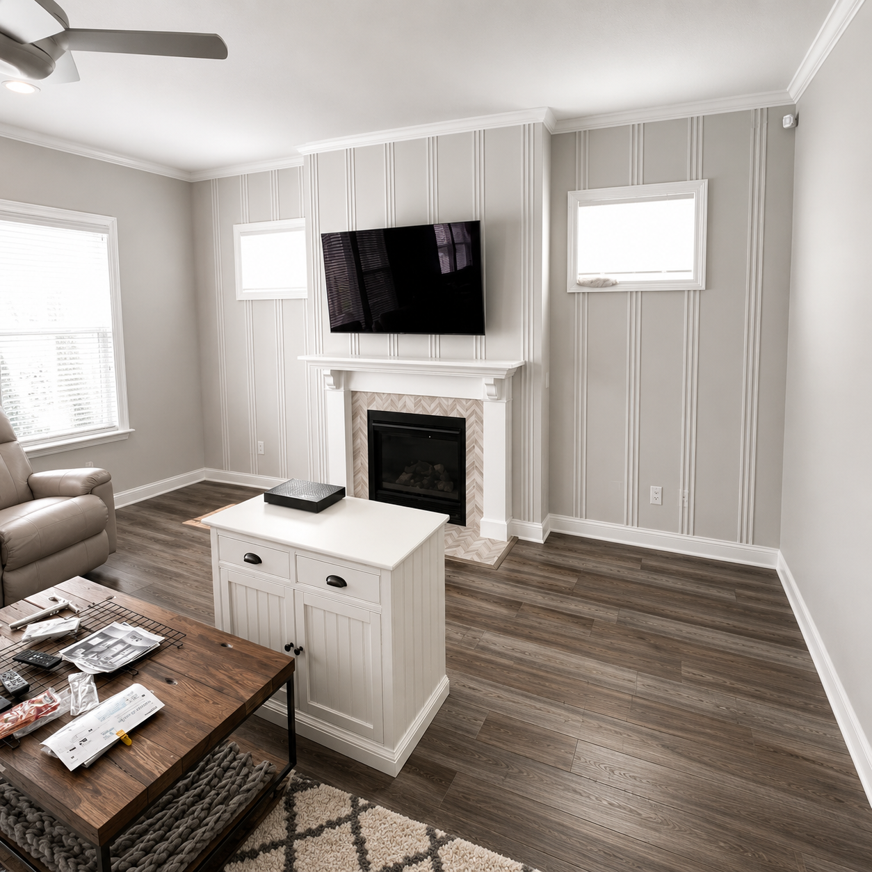 Living room with picture frame moulding on a painted accent wall behind a fireplace and mounted television
