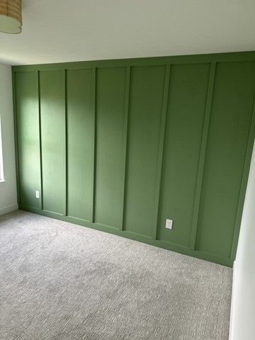 Bedroom wall finished in board and batten trim painted deep emerald green